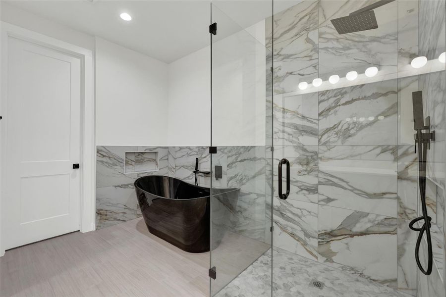 Bathroom with tile walls, a freestanding tub, a marble finish shower, and recessed lighting