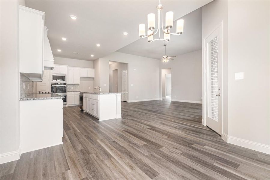 Kitchen with open floor plan, white cabinetry, backsplash, pendant lighting, and dark wood-style floors Kitchen with open floor plan, white cabinetry, backsplash, pendant lighting, and dark wood-style floors