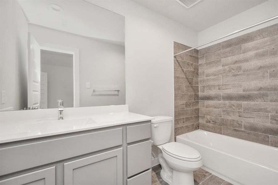 Experience sophistication in the secondary bathroom, where tile flooring complements a bath/shower combo with tile surround. Light wood cabinets complete with a beautiful light countertop, enhances the space for a truly inviting ambiance. Sample photo of completed home with similar floor plan. As-built interior colors and selections may vary.