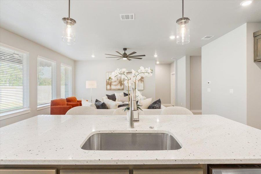Kitchen with a kitchen island with sink, light stone countertops, pendant lighting, recessed lighting, and open floor plan Kitchen with a kitchen island with sink, light stone countertops, pendant lighting, recessed lighting, and open floor plan