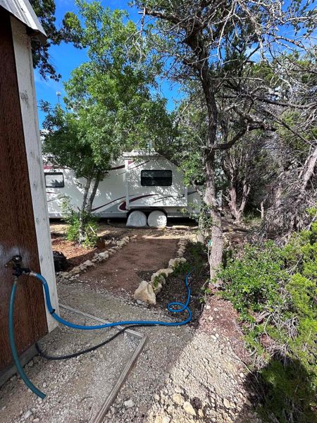 A tranquil, tree-filled landscape offers a private setting for an outdoor shed and RV.