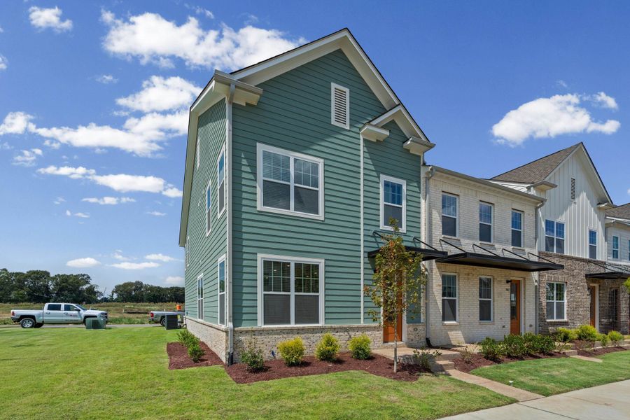 Two-story residence featuring horizontal siding, white trim windows, a light brick foundation, and a landscaped yard