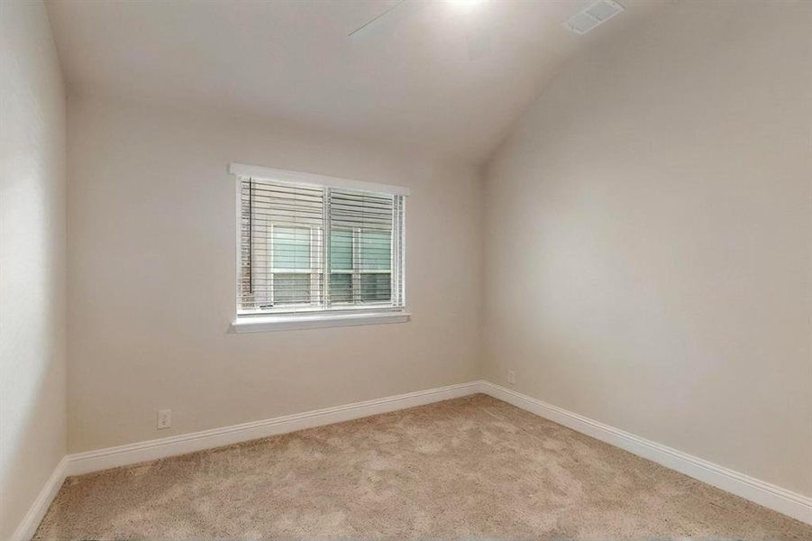 Carpeted spare room with lofted ceiling and baseboards