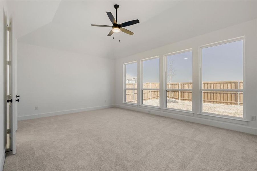 Unfurnished room with a ceiling fan, light carpet, and vaulted ceiling