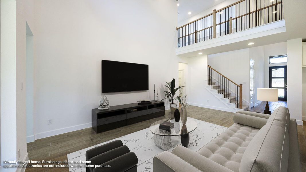 Living room with wood finished floors, a towering ceiling, stairway, and recessed lighting