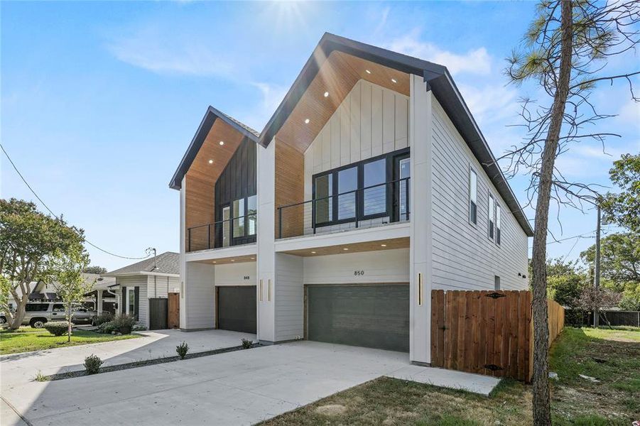Contemporary house with a balcony, an attached garage, driveway, and board and batten siding
