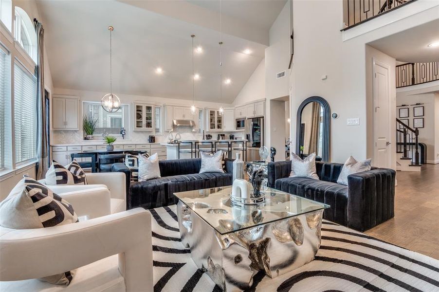 Living room featuring high vaulted ceiling, a chandelier, wood finished floors, stairs, and recessed lighting