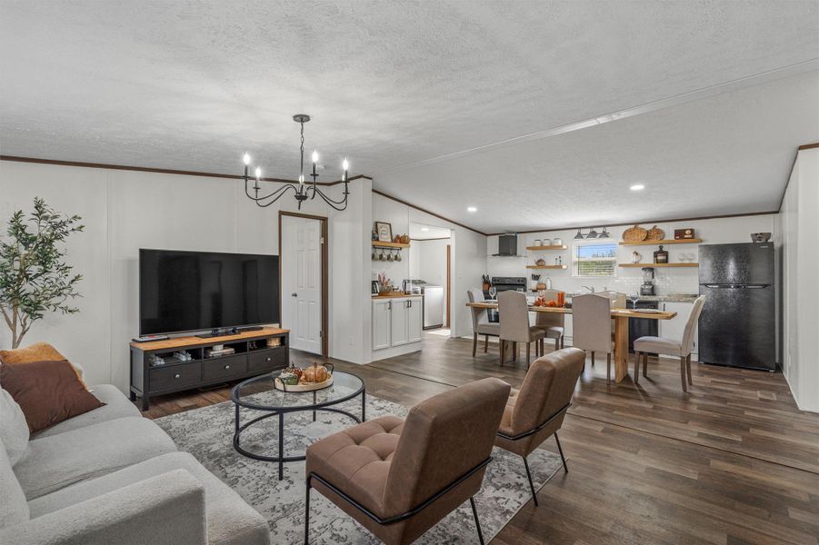 Living area featuring lofted ceiling, dark wood-style floors, a chandelier, crown molding, and a textured ceiling