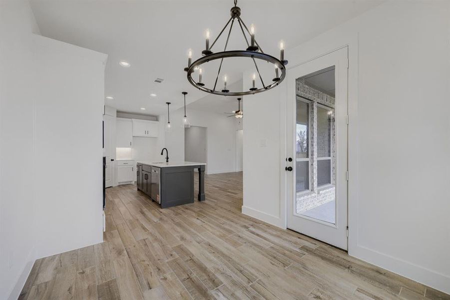 Open-concept living space with wood-finish flooring, a contemporary black chandelier, recessed lighting, and a glass-paneled exterior door