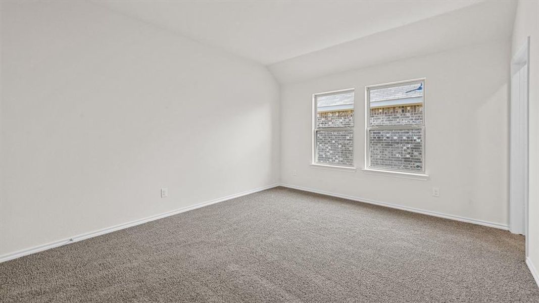 Empty room featuring carpet flooring and vaulted ceiling