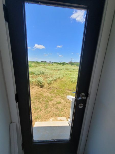 Uninterrupted vistas of natural landscape unfold through the glass entryway.