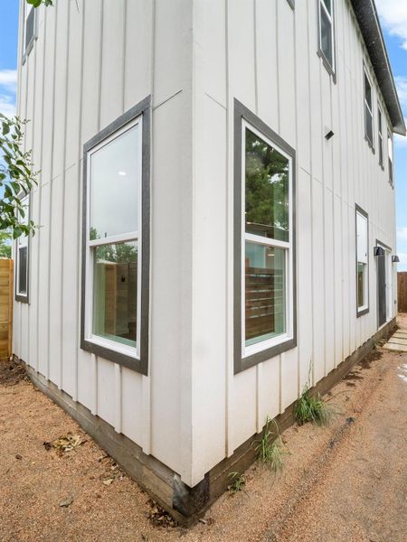Contemporary exterior featuring white vertical siding and dark-trimmed windows