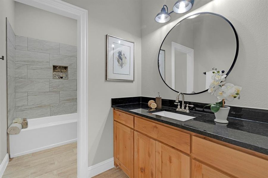 Bathroom featuring tiled shower / bath, vanity, and hardwood / wood-style floors