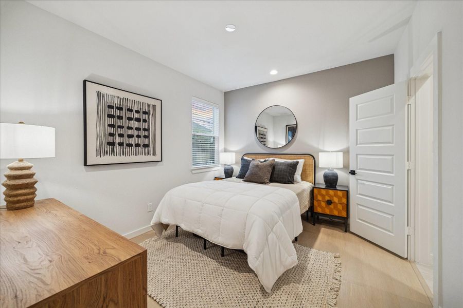 Secondary bedroom with a soothing neutral palette, accent wall, and warm natural light. Ideal for guests or a home office, offering comfort and privacy with an attached bath.