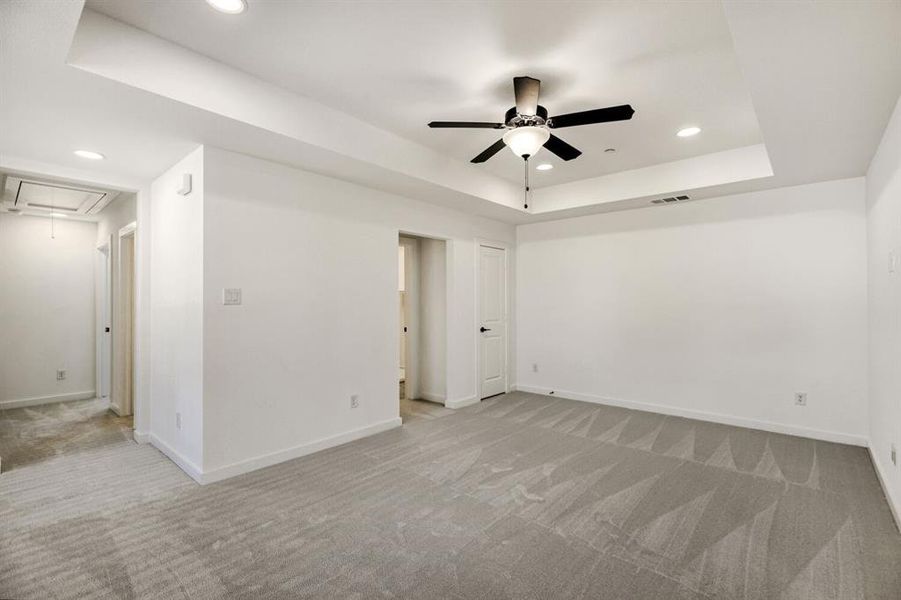 Unfurnished room with light colored carpet, recessed lighting, a raised ceiling, and ceiling fan