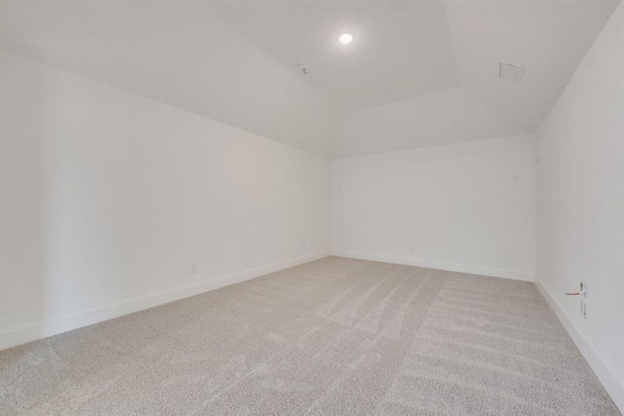 Empty room with light carpet and lofted ceiling Empty room with light carpet and lofted ceiling