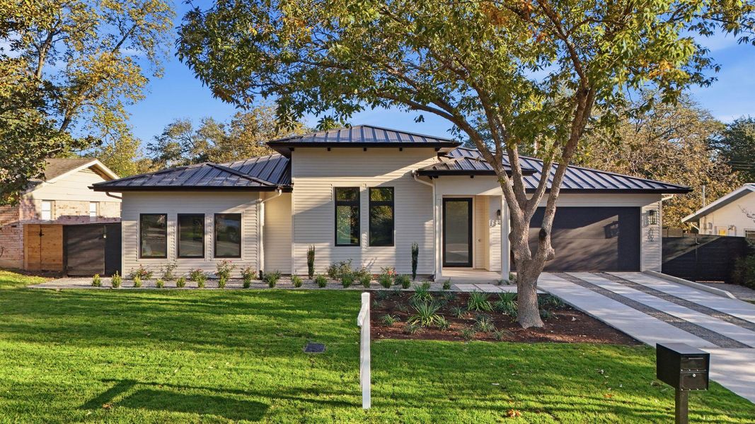 View of front of home featuring a standing seam roof, a metal roof, driveway, and a garage