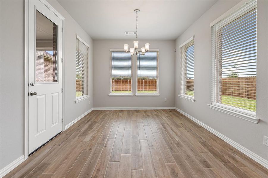 Unfurnished dining area featuring a chandelier and light wood-type flooring Unfurnished dining area featuring a chandelier and light wood-type flooring