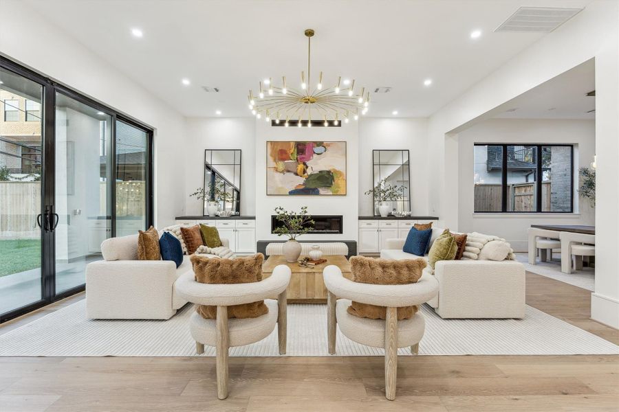 The open-concept living room, highlighted by a striking statement chandelier, features double-sliding door that leads to the backyard, allowing natural light to flood the space and offering beautiful views.