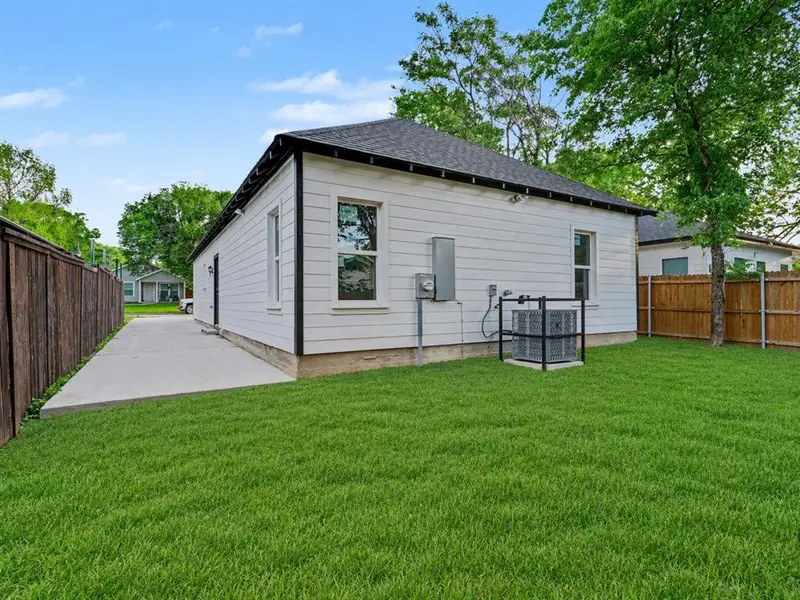 Expansive green lawn bordering a concrete driveway leading to the rear entrance