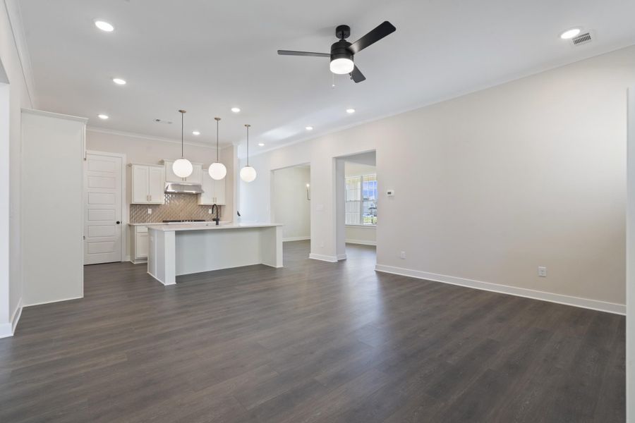 Unfurnished living room with dark wood finished floors, recessed lighting, a ceiling fan, and ornamental molding Unfurnished living room with dark wood finished floors, recessed lighting, a ceiling fan, and ornamental molding