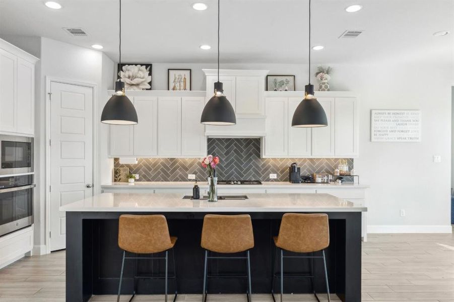 Kitchen with decorative backsplash, decorative light fixtures, white cabinetry, light wood-style flooring, and recessed lighting