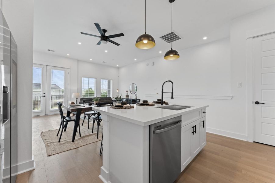 This centrally positioned kitchen island serves as a stylish anchor within the open-concept layout, offering clear sightlines to the dining area, living space, and the balcony beyond. Its placement encourages seamless interaction, whether prepping meals or entertaining guests, while natural light pours in through the nearby French doors. The island’s sleek design and functional surface make it a hub of activity tying together comfort and sophistication.