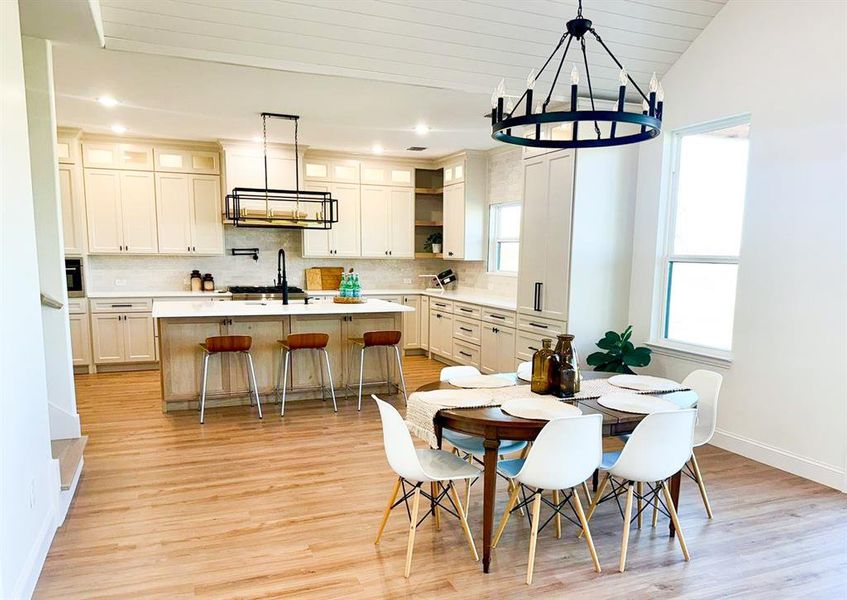 Dining space with a healthy amount of sunlight, vaulted ceiling, sink, and light hardwood / wood-style flooring