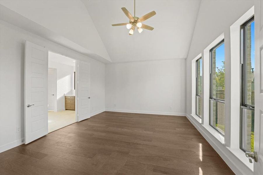 Unfurnished room featuring high vaulted ceiling, dark wood-type flooring, and a ceiling fan