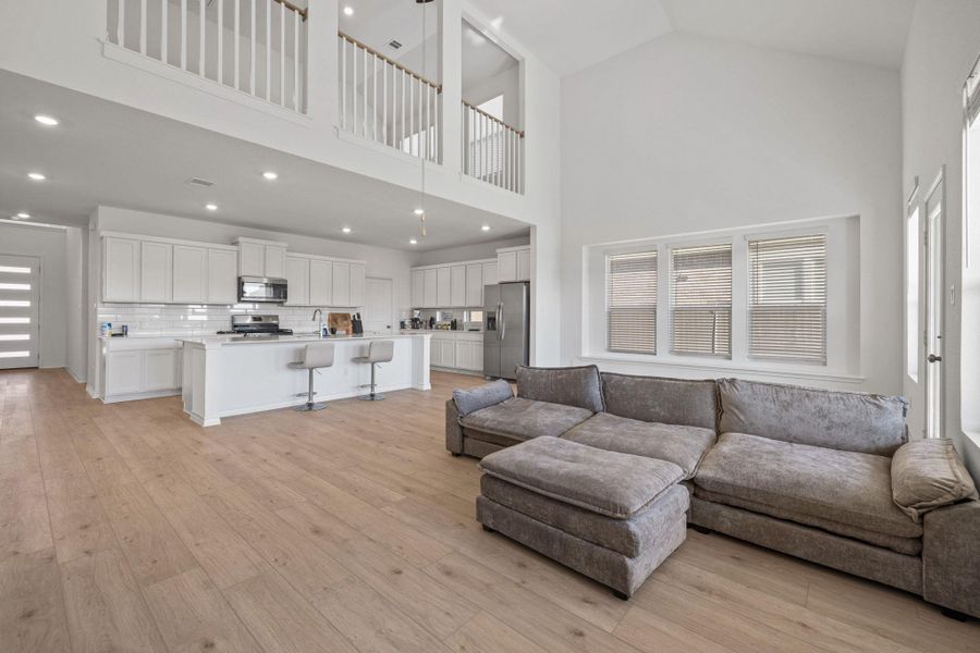 Living room featuring light wood finished floors, high vaulted ceiling, and recessed lighting