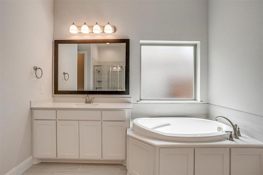 Bathroom featuring shower with separate bathtub, tile patterned flooring, and vanity