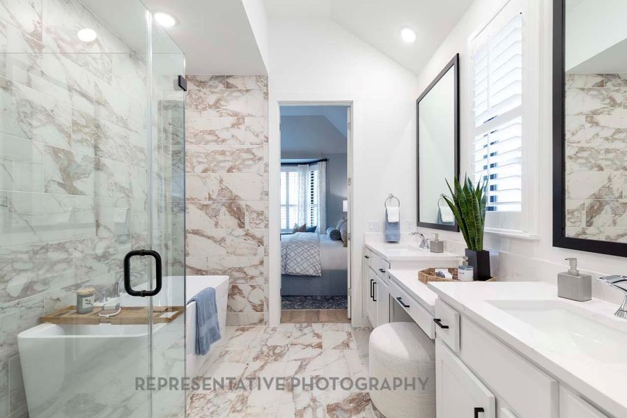 Ensuite bathroom with marble look tile flooring, tile walls, two vanities, a shower stall, and a soaking tub Ensuite bathroom with marble look tile flooring, tile walls, two vanities, a shower stall, and a soaking tub