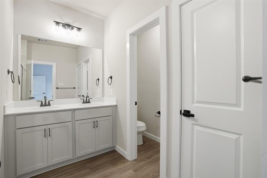 Bathroom featuring double vanity and light wood finished floors Bathroom featuring double vanity and light wood finished floors