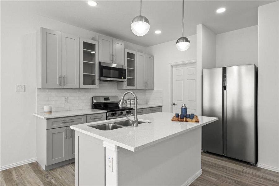 Kitchen with backsplash, wood finished floors, gray cabinets, and appliances with stainless steel finishes