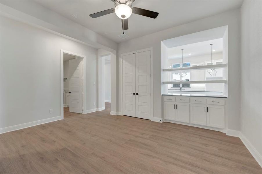 Unfurnished bedroom with ensuite bathroom, light wood-style flooring, ceiling fan, and a closet