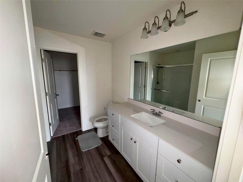 Full bathroom featuring a stall shower, vanity, dark wood-style flooring, and a spacious closet Full bathroom featuring a stall shower, vanity, dark wood-style flooring, and a spacious closet