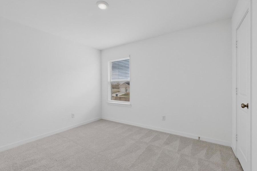 Unfurnished bedroom featuring light colored carpet and baseboards