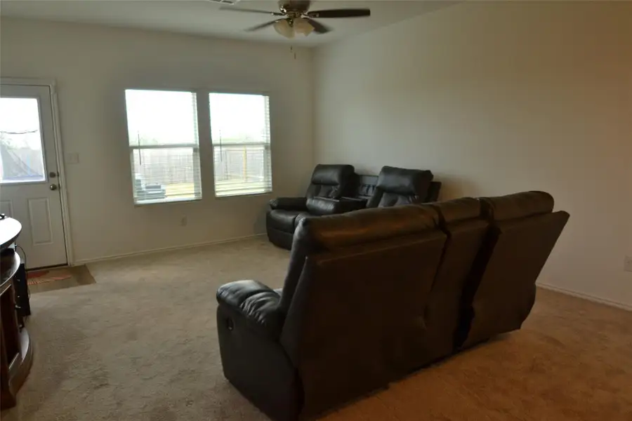 Living area featuring light colored carpet and ceiling fan