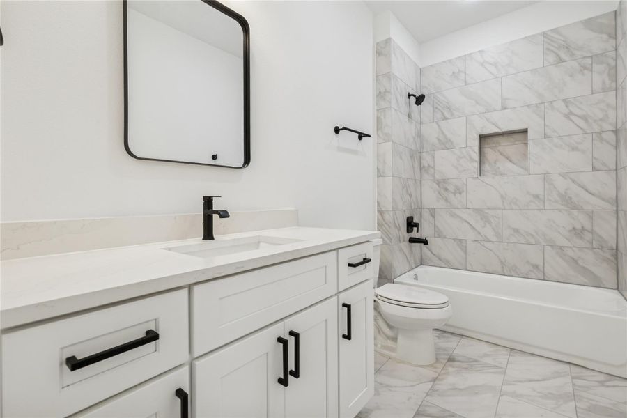 This bathroom features a modern design with a white vanity, black fixtures, and a sleek mirror. The shower area has elegant gray marble tiles, and the space is bright and clean. This bathroom features a modern design with a white vanity, black fixtures, and a sleek mirror. The shower area has elegant gray marble tiles, and the space is bright and clean.
