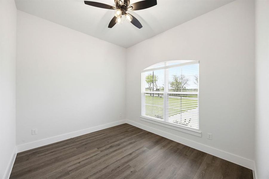 Room featuring a vaulted ceiling with a ceiling fan, an arched window with blinds, wood-finish flooring, and white baseboards