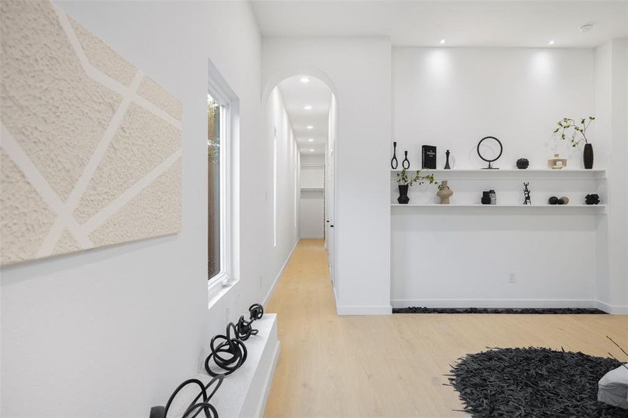 Hallway featuring light wood-type flooring, arched walkways, and recessed lighting