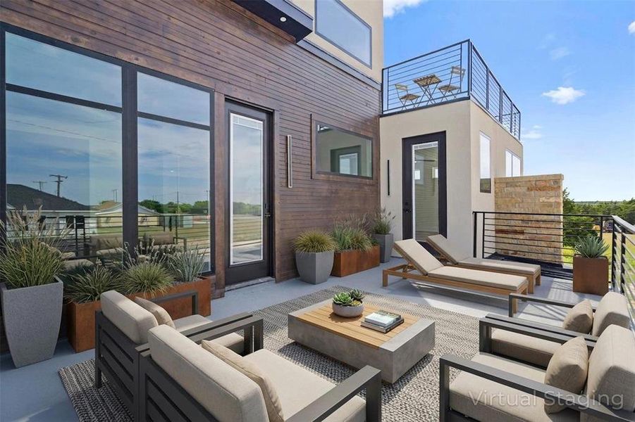 Expansive outdoor patio area featuring a modern wood slat accent wall, large floor-to-ceiling windows, and a private upper deck with railings Expansive outdoor patio area featuring a modern wood slat accent wall, large floor-to-ceiling windows, and a private upper deck with railings