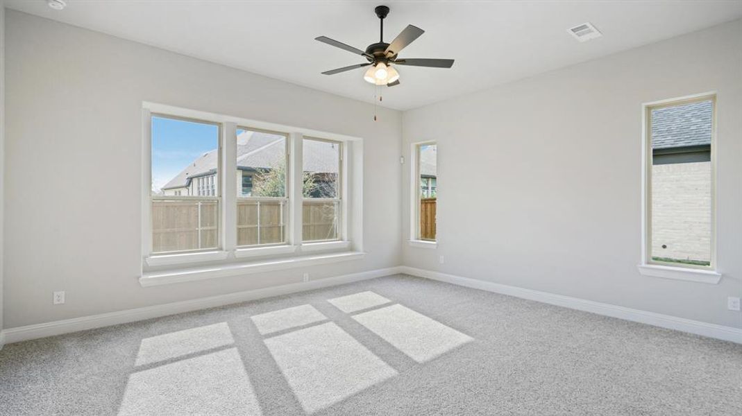 Unfurnished room featuring carpet, healthy amount of natural light, and ceiling fan Unfurnished room featuring carpet, healthy amount of natural light, and ceiling fan