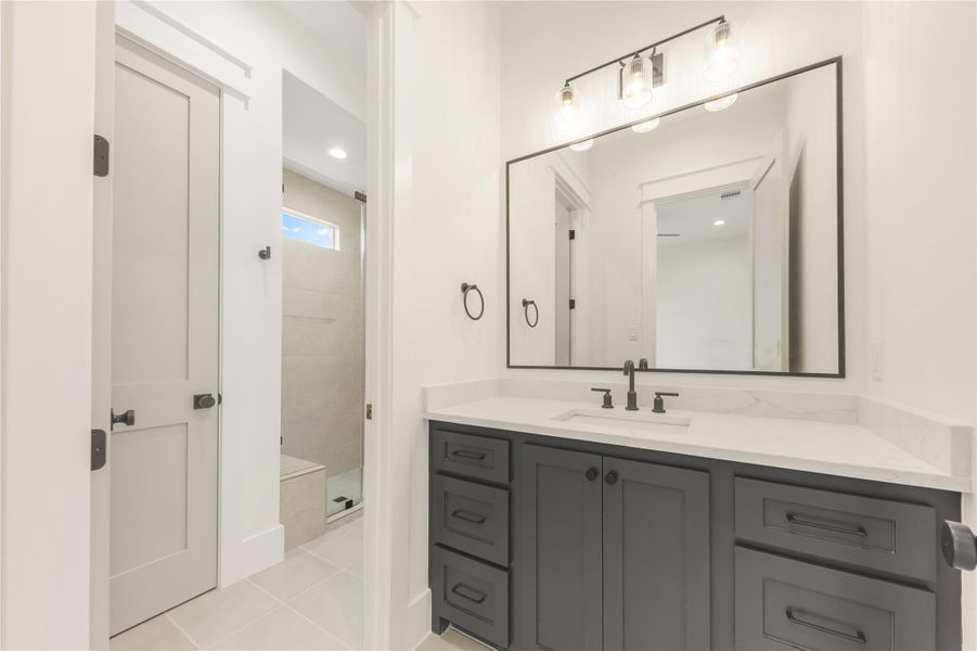 Full bathroom with vanity, light tile patterned flooring, and a stall shower