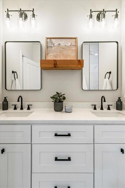 Double vanity featuring white shaker cabinetry, matte black hardware, and an integrated countertop with dual sinks
