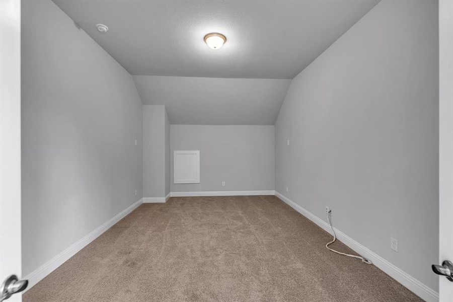 Bonus room with light carpet and vaulted ceiling