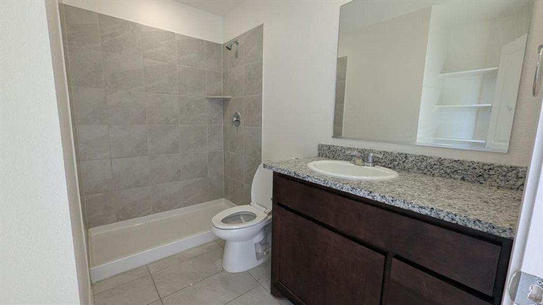 Full bathroom with vanity, a tile shower, and tile patterned floors Full bathroom with vanity, a tile shower, and tile patterned floors