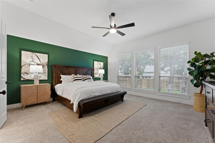 Spacious room featuring vaulted ceilings, plush carpet flooring, and a ceiling fan with integrated lighting