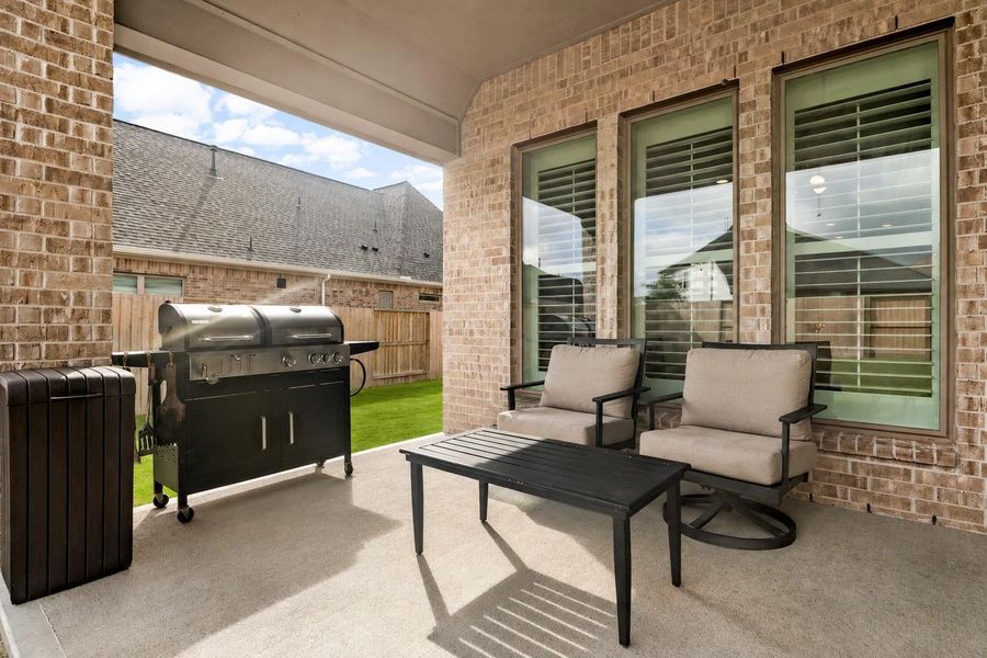 Covered patio overlooking a large backyard perfect for outdoor activities & entertaining.