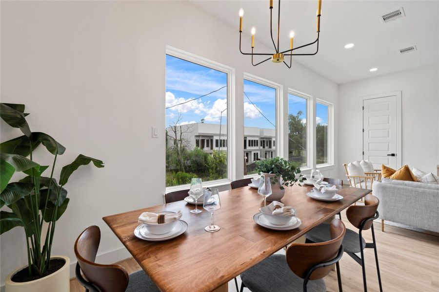 Framed by corner windows and elevated by designer lighting, the dining room balances warmth and sophistication.